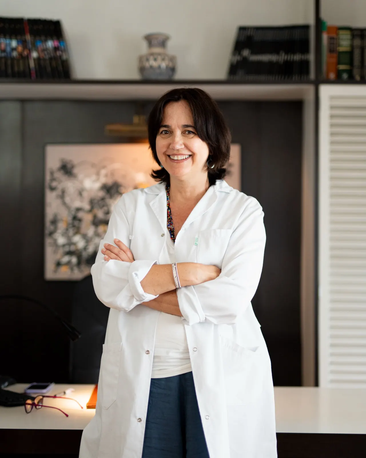 La Dra. Victòria Andreu, amb bata blanca i els braços creuats, al seu despatx